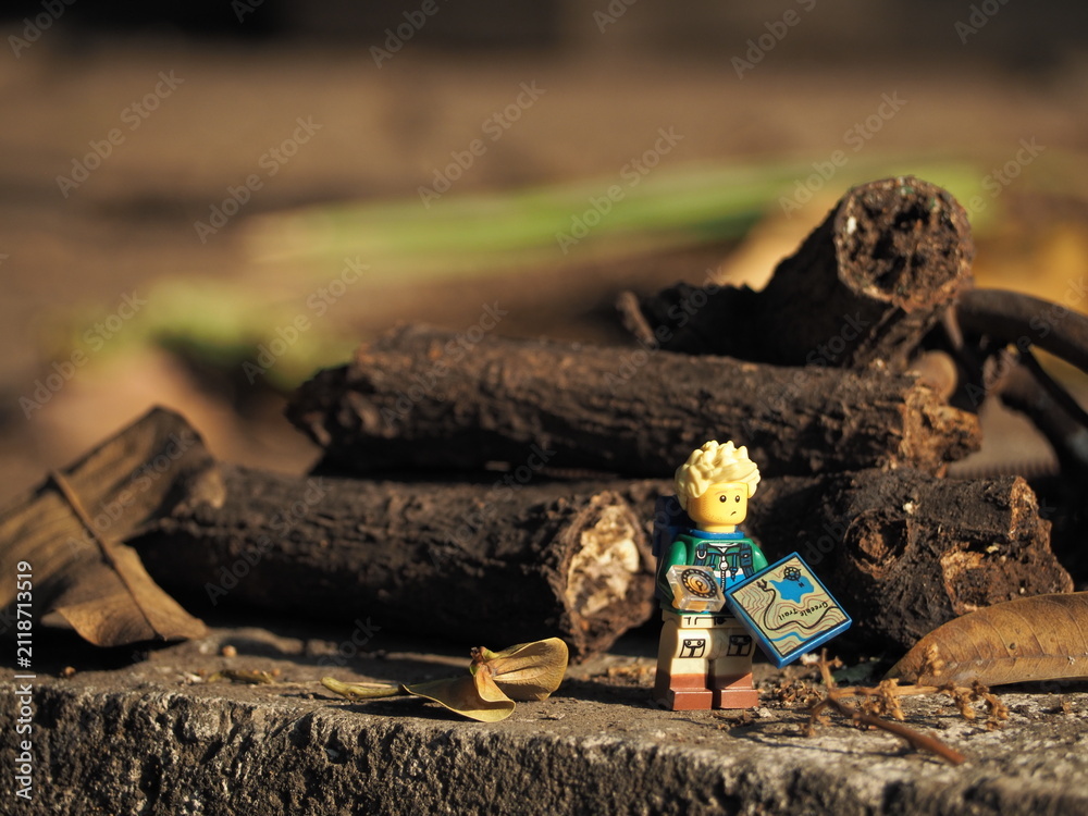 Fototapeta premium Indonesia - September 12, 2025 : Mini toy of action figure at table with blurred background. Miniature photography concept design. Minifigure of traveler man character with map and bag at outdoor.