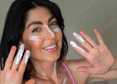 Beautiful  Smiling Woman applying sunscreen lotion on her face
