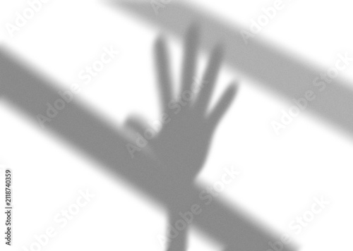 Shadow of a human hand reaching out with diagonal lines cast across a flat surface