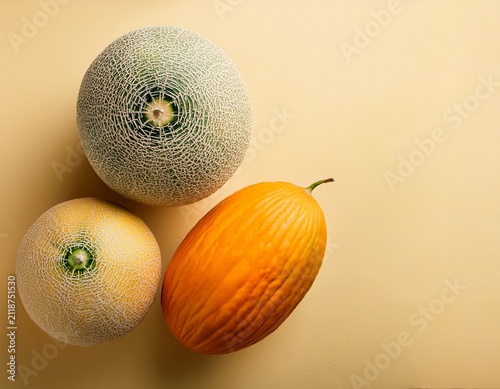 Top view of white and orange melons, whole and sliced, on pale yellow background with copy space