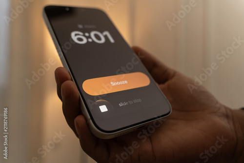 Photography Hand Snoozing Alarm on Smartphone.