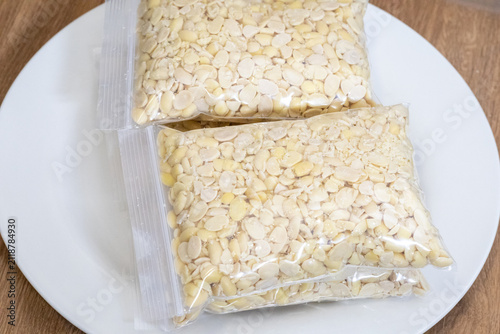 Peeled split soybeans packed tightly in a clear plastic zipper pouch, presented on a plain white surface. Highlighting raw plant based ingredients, prep work