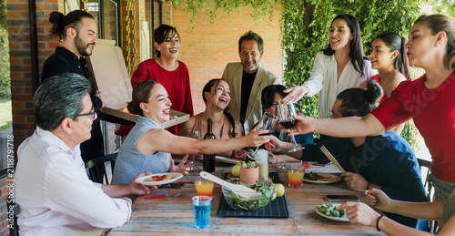 large group of latinos friends or multi generation family eating pizza and having a dinner in a terrace party in Mexico Latin America, hispanic diverse, multi age and multicultural people