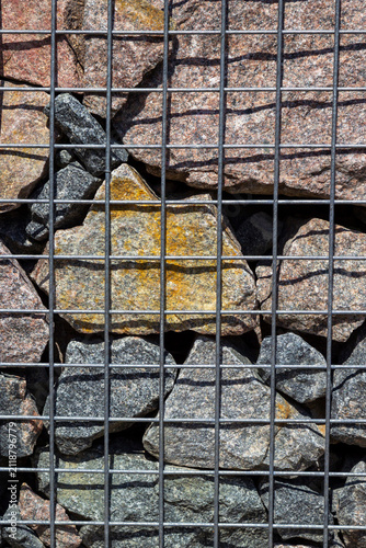 Large granite stones in a metal mesh. Gabion for a park.