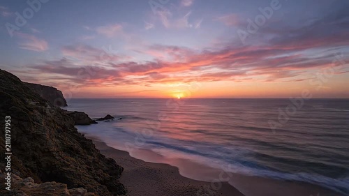 A golden sunset illuminates the rugged cliffs above the ocean