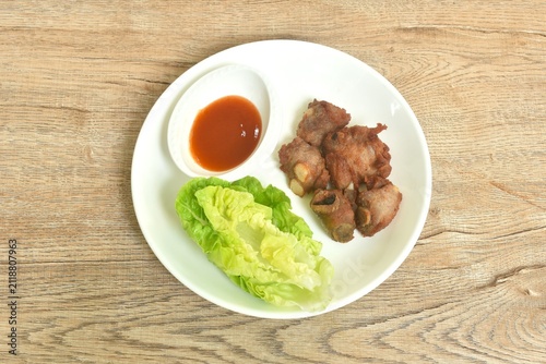 fried fermenting pork cartilage bone with garlic with cos lettuce salad dipping chili sauce on plate