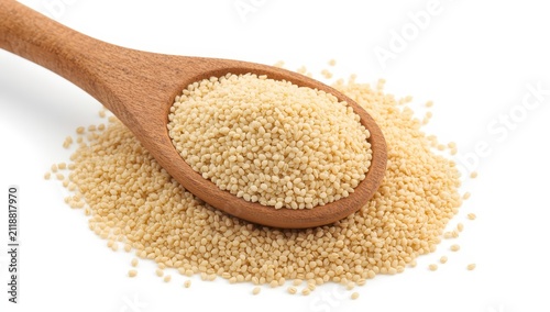 Wooden spoon with raw organic semolina on white background, side angle.