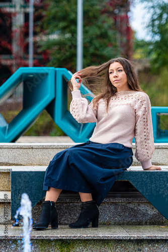 Young Woman Posing Elegantly on Steps by Modern Art Installation in Urban Setting