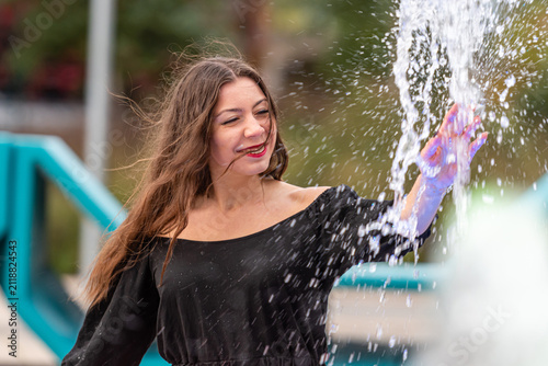 Joyful Woman Playing in Splashing Water at Outdoor Park in Bright Sunshine