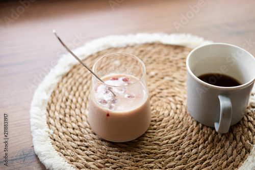 Refreshing homemade iced coffee with frozen cherry juice cubes served beside a cup of black coffee. Cozy home preparation concept with natural light and rustic styling.