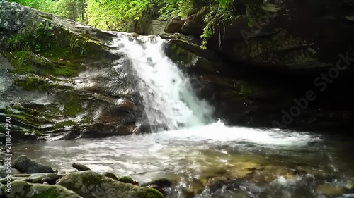 A serene forest waterfall cascading over mossy rocks into a tranquil pool