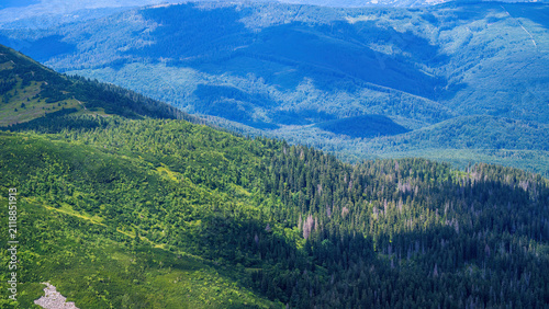 Aerial view of Babia Gora mountain landscape showing forested slopes, mountain valleys, and the Poland-Slovakia border region with coniferous trees and alpine meadows during summer.