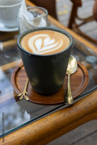 Foto Cup of freshly prepared latte with heart-shaped latte art served at a cozy outdoor cafe