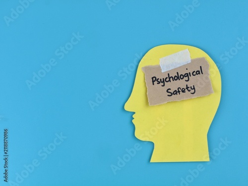 Psychological safety concept handwritten with human head paper silhouette on blue background. Ideal for business management, human resources, workplace culture, team trust and mental health awareness