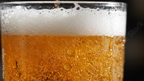 Refreshing golden beer poured into glass, close-up, bubbles rising, frothy head forming