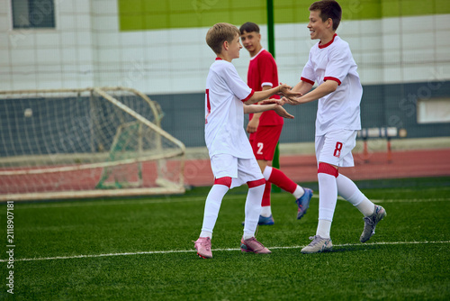 Cuadro en lienzo Teenage male football teammates congratulating each other after successful play