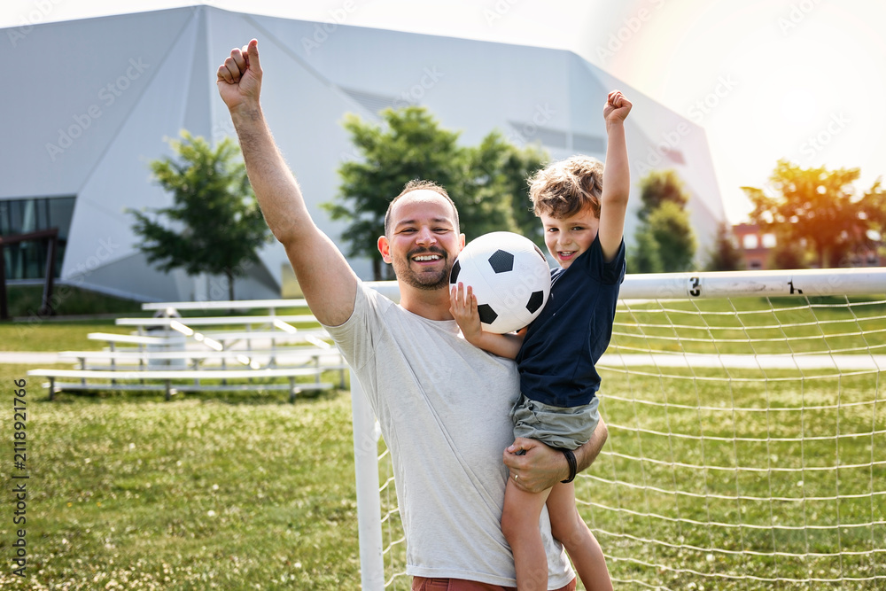 Obraz premium man with child playing football outside on field