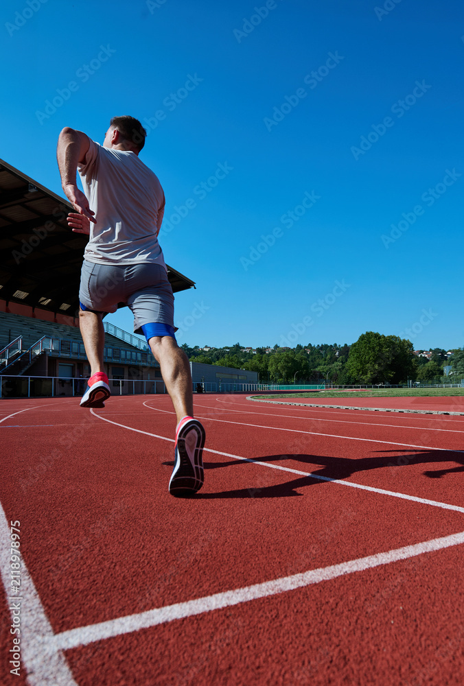 Obraz premium Male runner sprinting away on outdoor athletics track