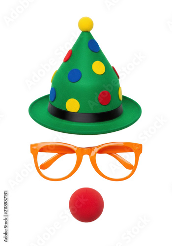 whimsical abstract face of a green felt conical clown hat, glossy orange novelty glasses, and a matte red foam nose, isolated in a high-key studio setting. concept of graphic commercial fun