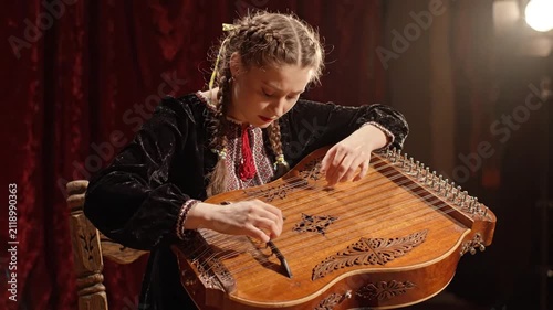Young woman plays traditional Ukrainian bandura instrument, folk music, cultural heritage