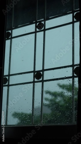 Window View from Inside Room Looking at Heavy Rain and Lightning Flash with Water Droplets on Glass