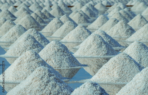 Sea salt piles in traditional salt farm during solar evaporation process for natural sodium chloride production and sustainable mineral harvesting in Thailand. Organic sea salt crystallization.