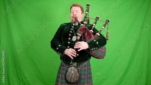 Man in kilt plays bagpipes on green screen