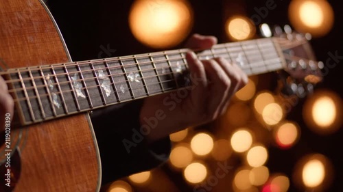 Close up of hands playing acoustic guitar with bokeh lights background