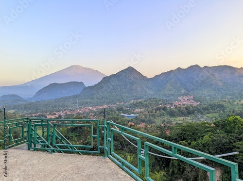Fotografía Scenic mountain view with forested hills, village, and volcano peak from observa