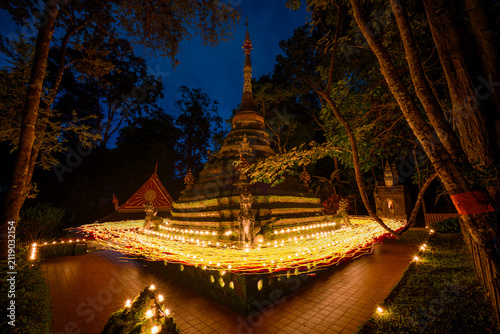 Candlelight procession around ancient pagoda at Wat Pha Lat on Asalha Bucha Day at night in Chiang Mai, Thailand. Candle trails and spiritual Buddhist ceremony concept.