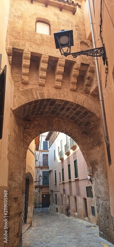 Palma's old town narrow cobbled streets, arch corridor connects two houses and stone walls go up rising the houses.Palma's  cobbled streets, reflex architectural heritage cultural background. Palma 
