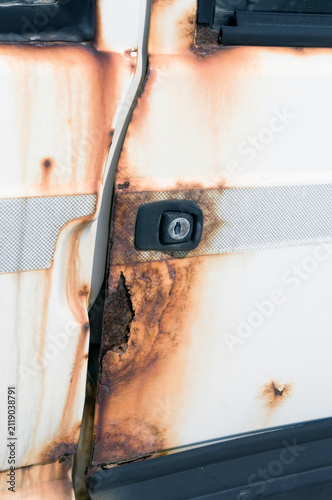 the rusted door of a white car