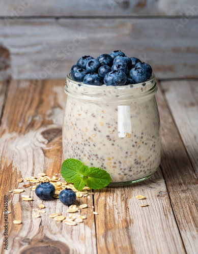A glass jar of overnight oats made with oat milk and chia seeds topped with fresh blueberries in morning.