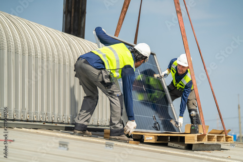 Konstfotografi Two professionals safely installing solar panels on a rooftop beneath a bright c