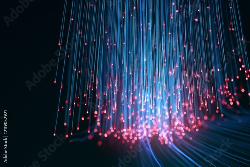 Colorful light strands hang down in a dark space showcasing the beauty of fiber optics at night during a technology event
