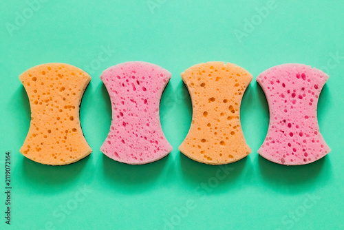 Vibrant kitchen sponges arranged on a solid mint green background, showcasing reusable cleaning supplies in a fresh, minimalist household hygiene composition.