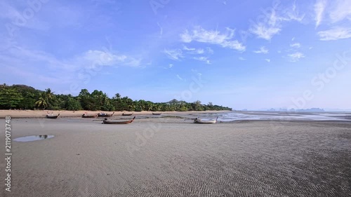 Line of longtail boats resting on rippled tidal flats at low tide