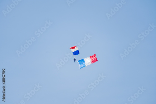 Paris, France - 14 Jun 25: Parachutist carrying French flag above Air and Space Museum