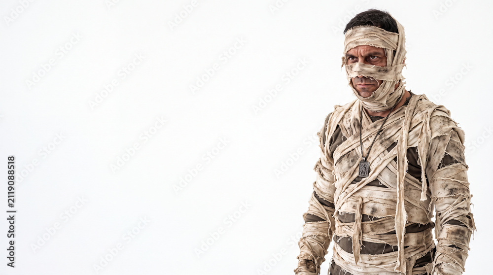 Fototapeta premium A young Hispanic man dressed as a mummy, wrapped in bandages with a distressed expression. The background is plain white, emphasizing the costume.