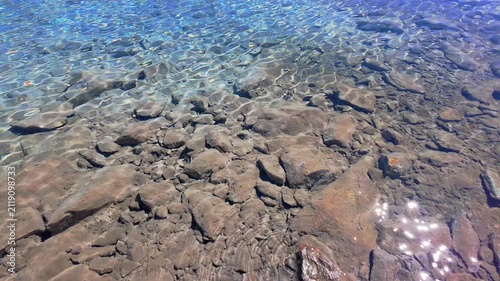 Sunlight Reflecting on Clear Rocky Water of Mountain Lake