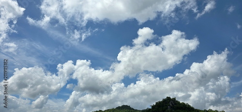 Bild auf Leinwand Bright blue sky with large white clouds floating above lush green mountains