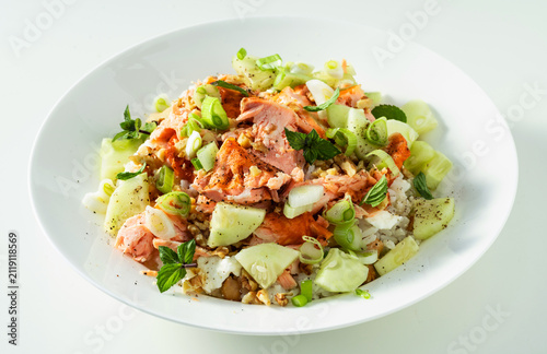 Baked salmon salad with cucumbers, chickpeas, walnuts, feta and rice on white background