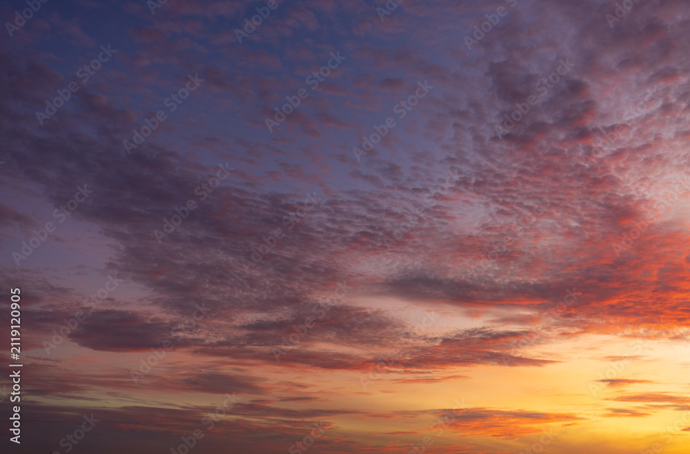 Fototapeta premium Vibrant Purple and Orange Sunset Sky with Textured Clouds,A breathtaking view of a dramatic sunset sky filled with vibrant purple, blue, and fiery orange clouds, creating a stunning colorful backgroun