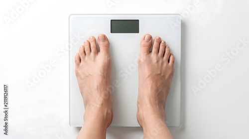 Bare feet standing on a white digital bathroom scale