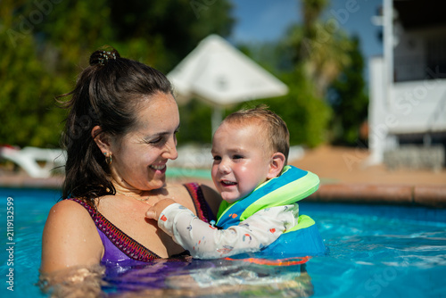 Mother holding toddler in swimming pool