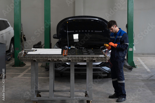 EV car maintenance garages. Technician diagnosing electric car vehicles battery, high-voltage battery service and general electric vehicle care at auto workshop