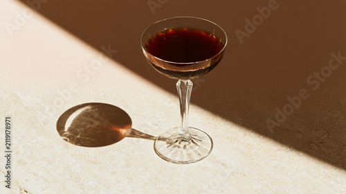 Dark cocktail in coupe glass casting shadow in sunlight