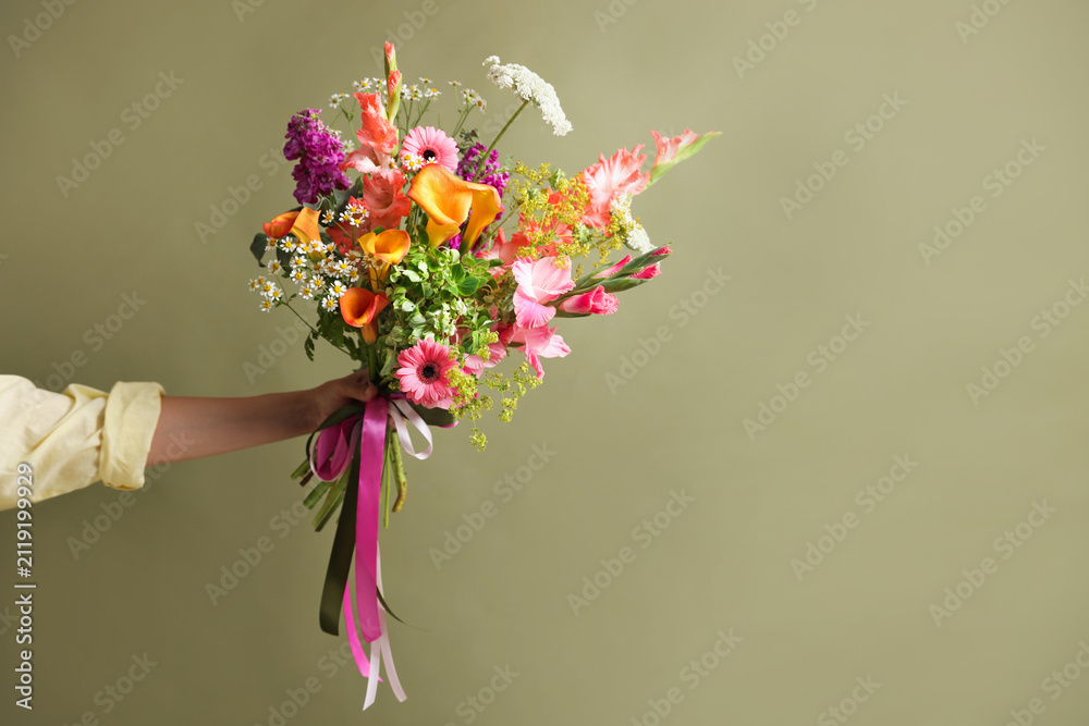 Obraz premium Woman with bouquet of beautiful vibrant flowers on olive background, closeup. Space for text