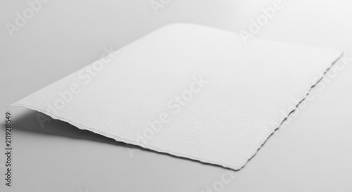Blank textured paper sheet with deckled edge, isolated on light grey background.
