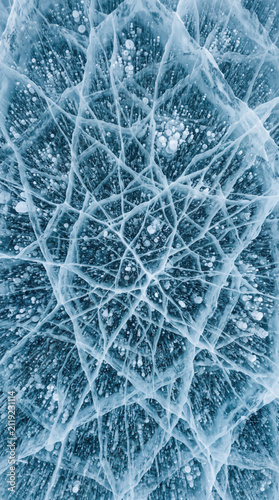 Macro texture of cracked blue ice with frozen air bubbles